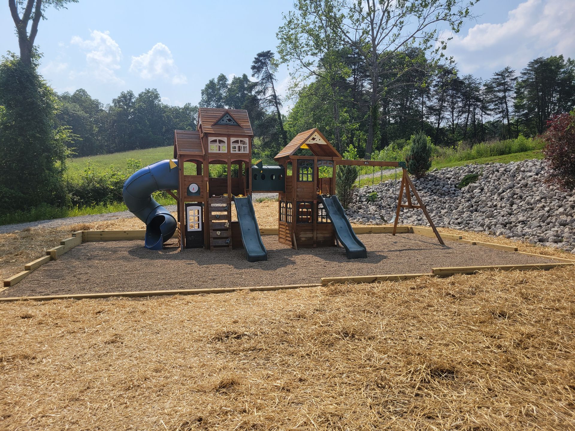 Playground with wooden structures, slides, and swings surrounded by wood chips.