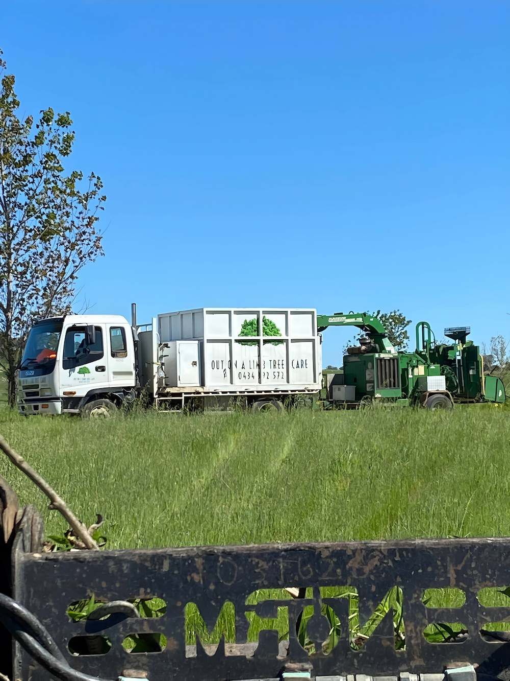 A Truck Is Parked In A Grassy Field Next To A Machine — Out On A Limb Tree and Garden Care In Tuross Head, NSW