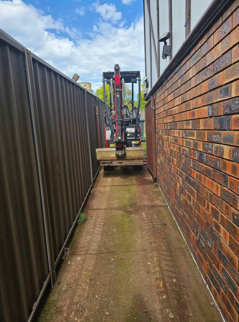 A Small Orange And Black Excavator Is Moving Rocks With A White Truck In The Background— Out On A Limb Tree and Garden Care In Broulee, NSW