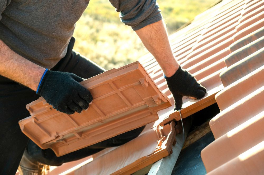 Closeup Of Worker Hands Installing Yellow Ceramic Roofing Tiles — ACT Roofing in Googong, NSW