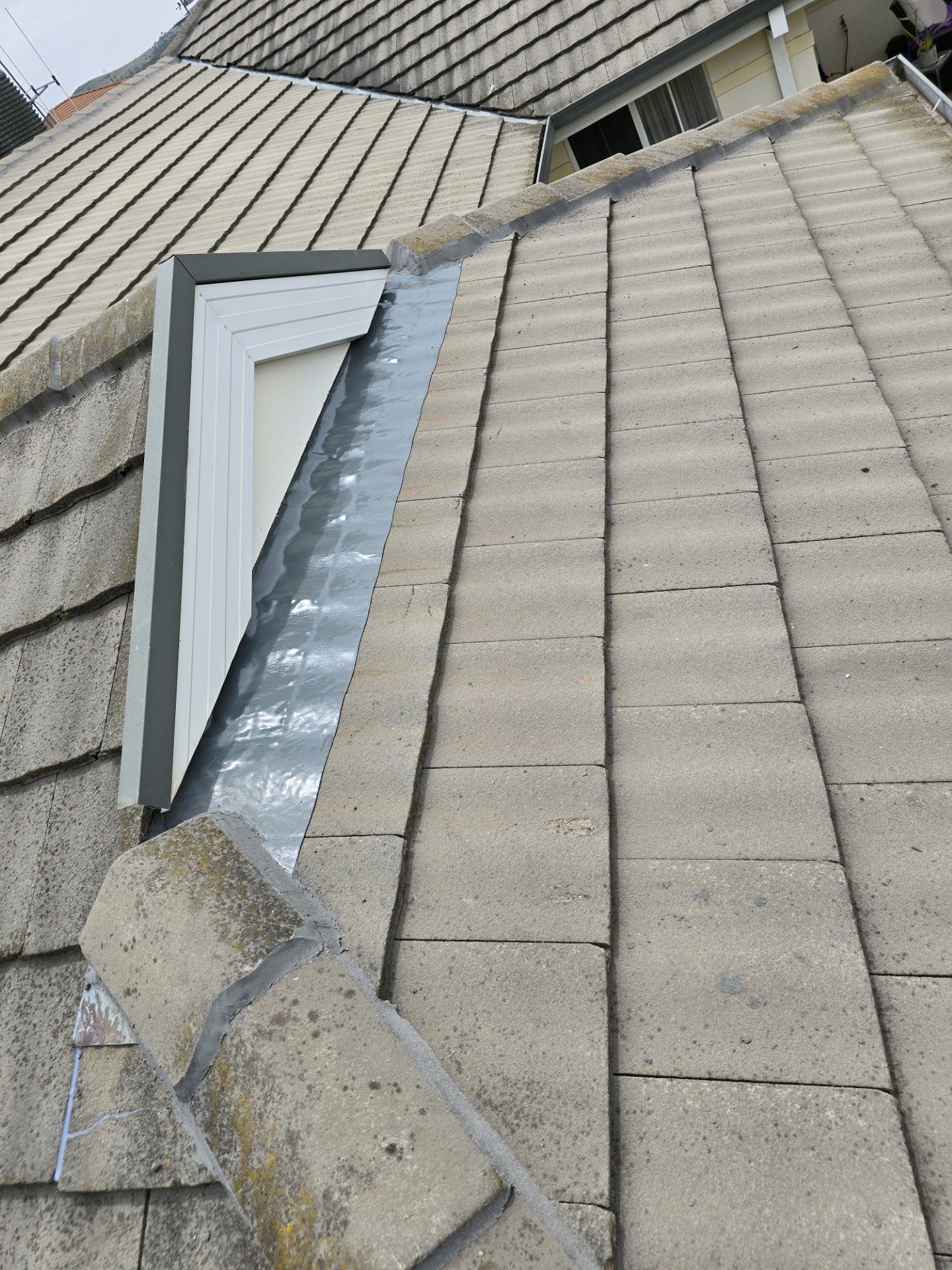 A Skilled Man Is Applying Leak Protecting Later On Top Of A Tiled Roof — ACT Roofing in Ngunnawal, ACT