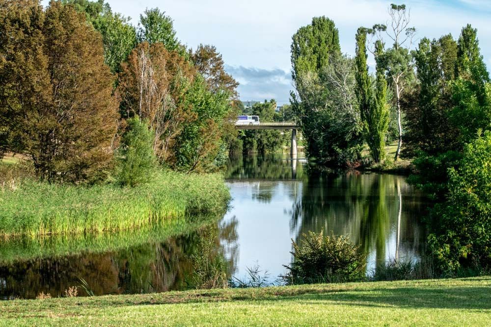 A Wide Greenery View of Queanbeyan River with Trees and a Bridge — ACT Roofing in Queanbeyan, NSW