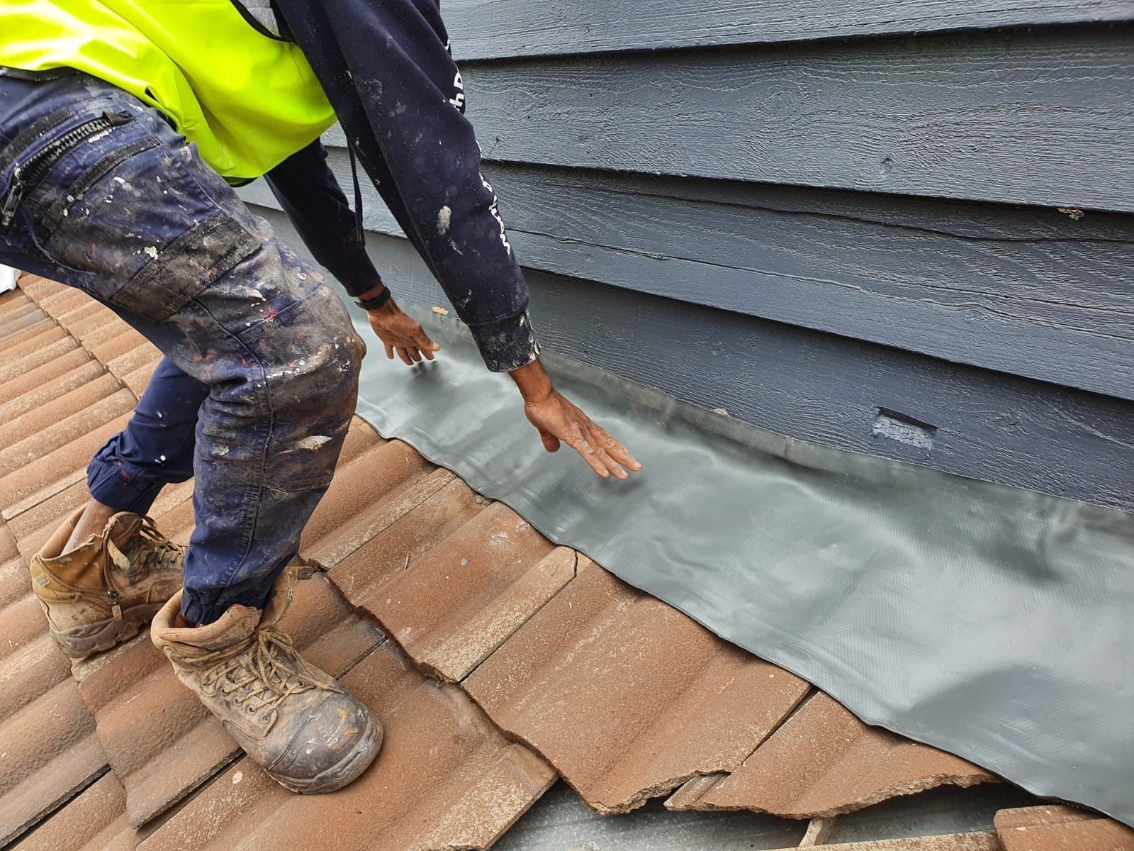 Worker Installing Roof Flashing on Tiled Roof