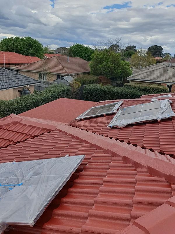 New Painted Red Tiled Roof With Two Solar Panels Installed On It — ACT Roofing in Ngunnawal, ACT