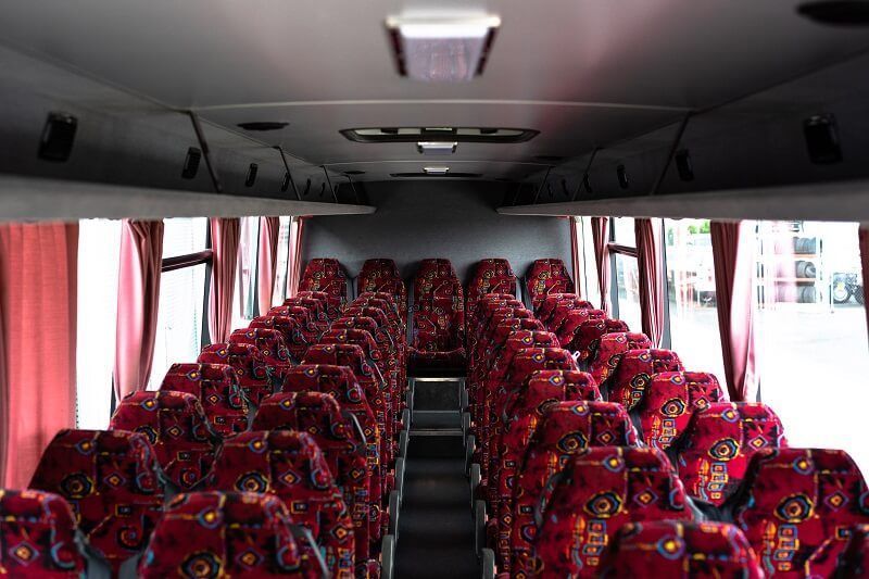 Empty Bus Interior With Rows of Red Patterned Seats — J & B Bus and Coach Pty Ltd In Kingscliff, NSW