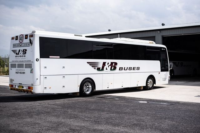 White J&B Buses Coach Parked Outside a Garage — J & B Bus and Coach Pty Ltd In Tweed Heads, NSW