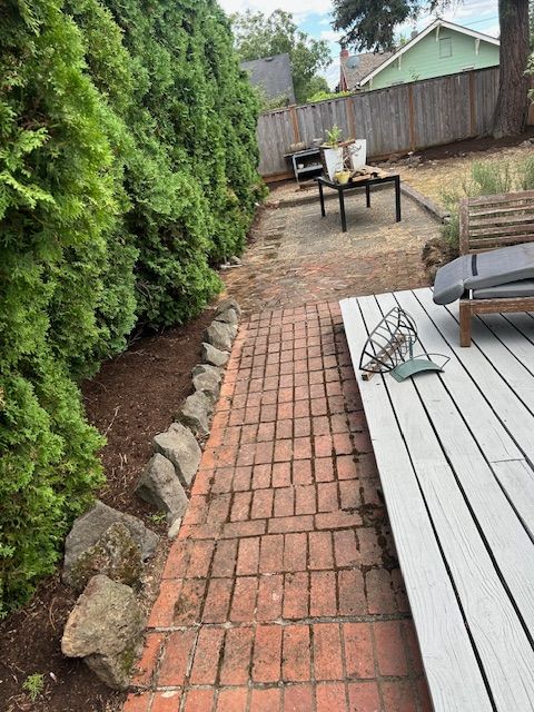 A brick walkway leads to a deck with a table and chairs