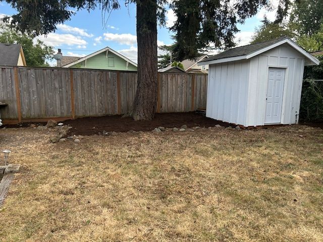 A backyard with a white shed and a wooden fence.