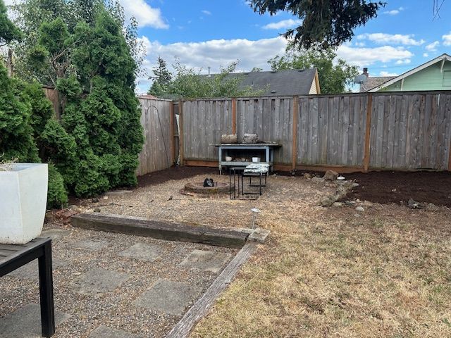 A backyard with a wooden fence and a fire pit.