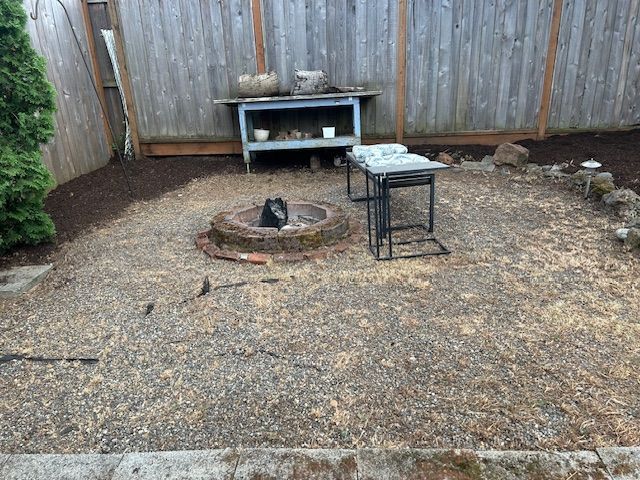 A cat is sitting in a fire pit in a backyard.