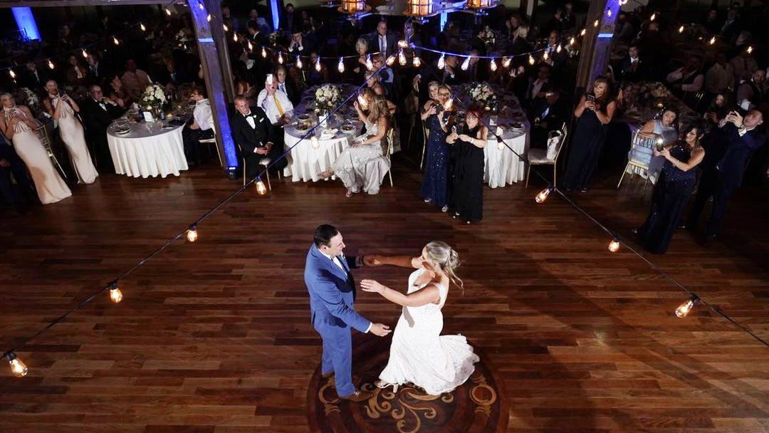 A bride and groom are dancing their first dance at their wedding reception.