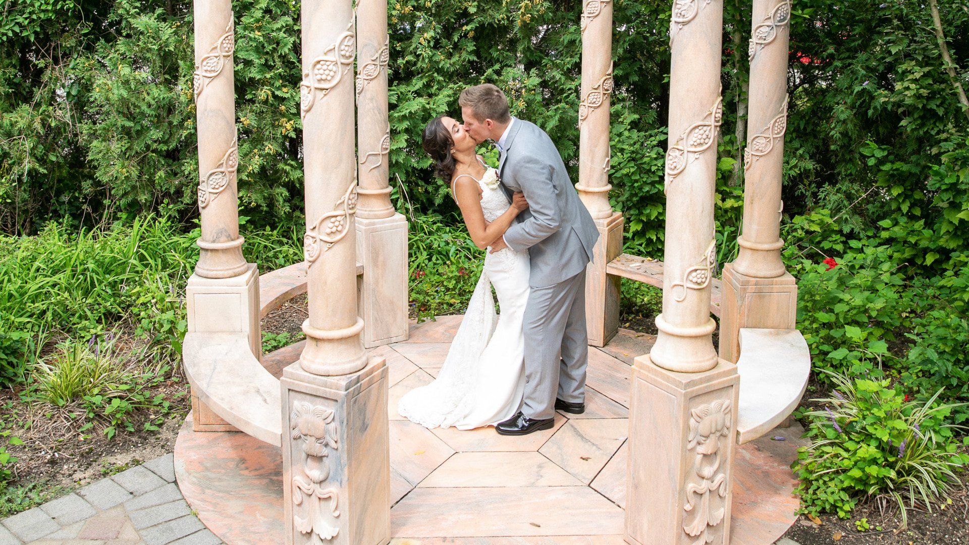 A bride and groom are kissing under a gazebo.