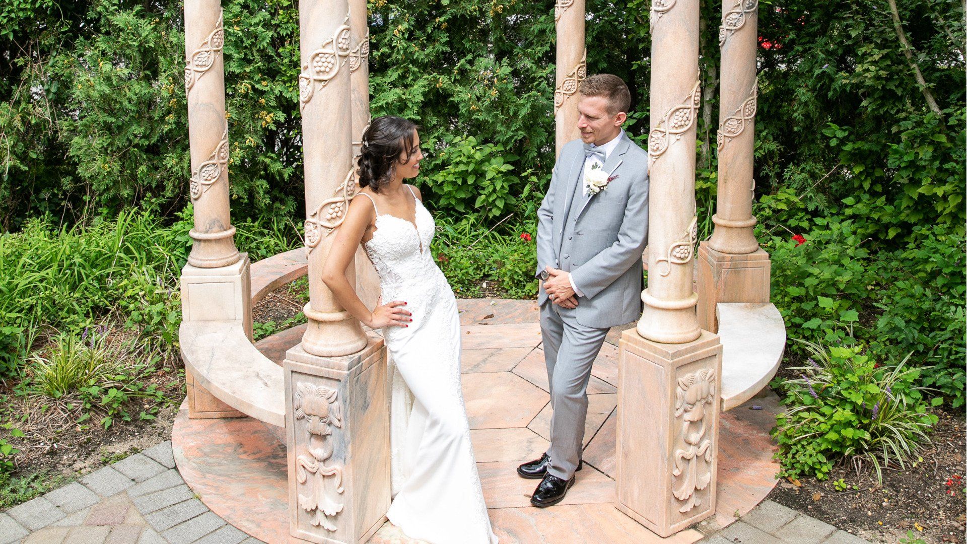 A bride and groom are posing for a picture in front of a gazebo.