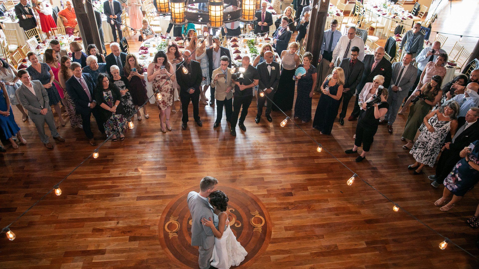 A bride and groom are dancing in front of their wedding guests.