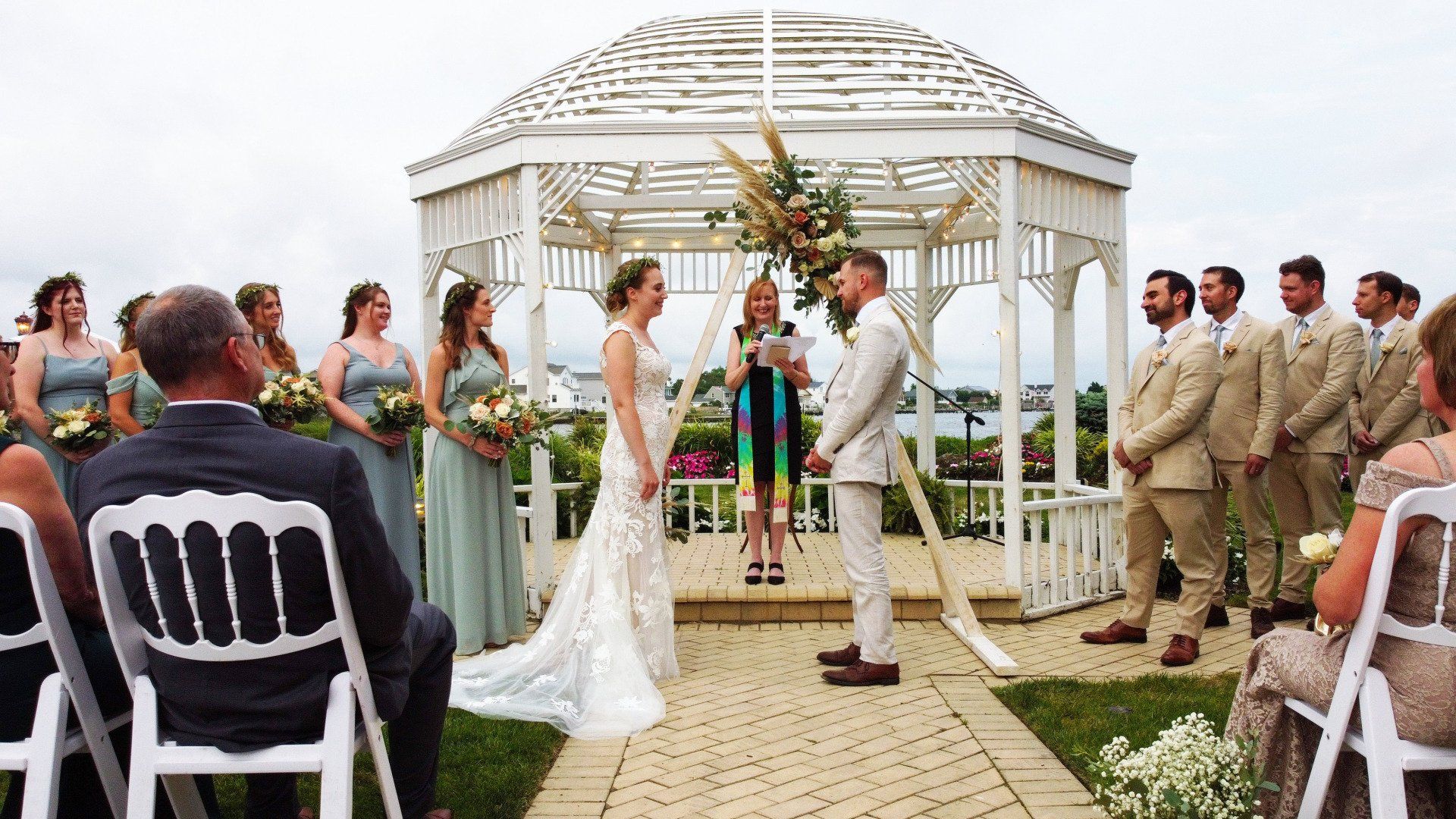 A bride and groom are getting married in front of a gazebo.