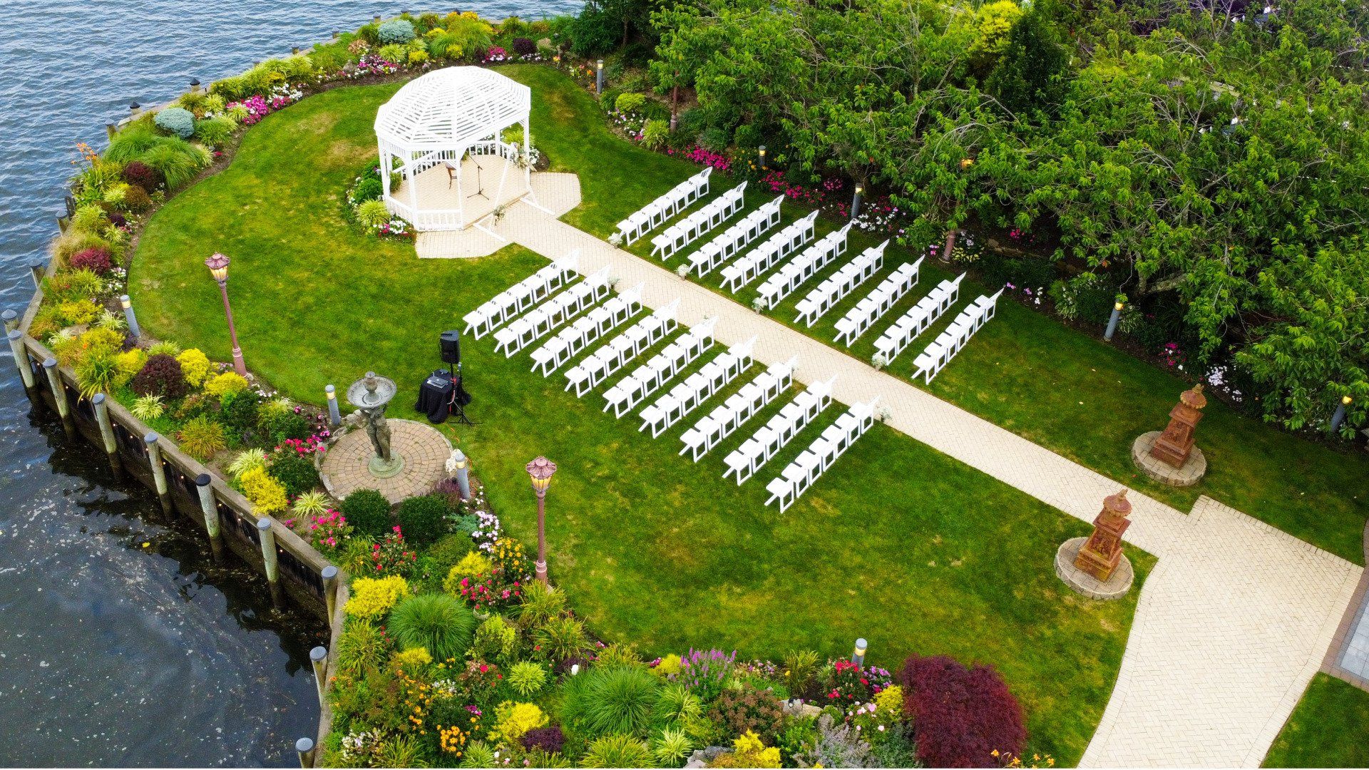 An aerial view of a wedding ceremony taking place on a small island in the middle of a lake.