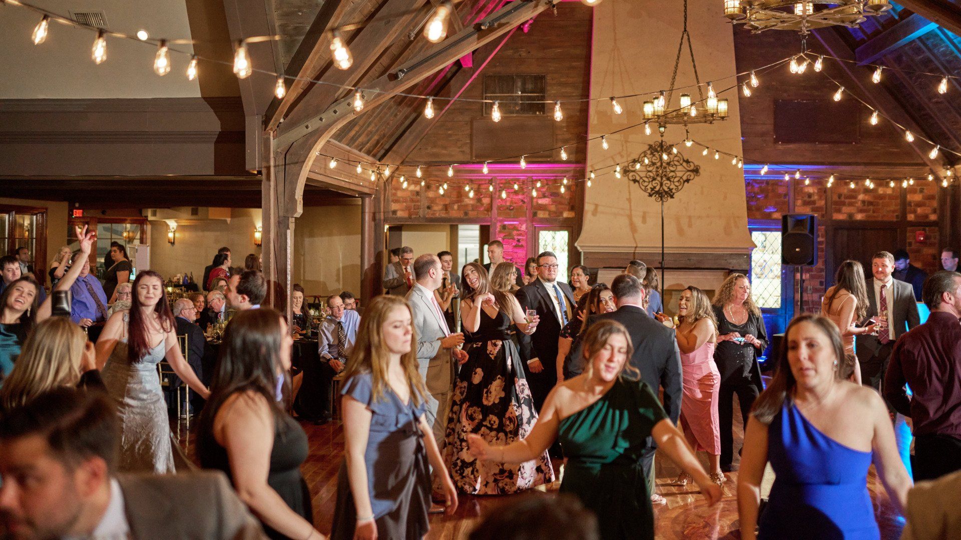 A large group of people are dancing at a wedding reception.