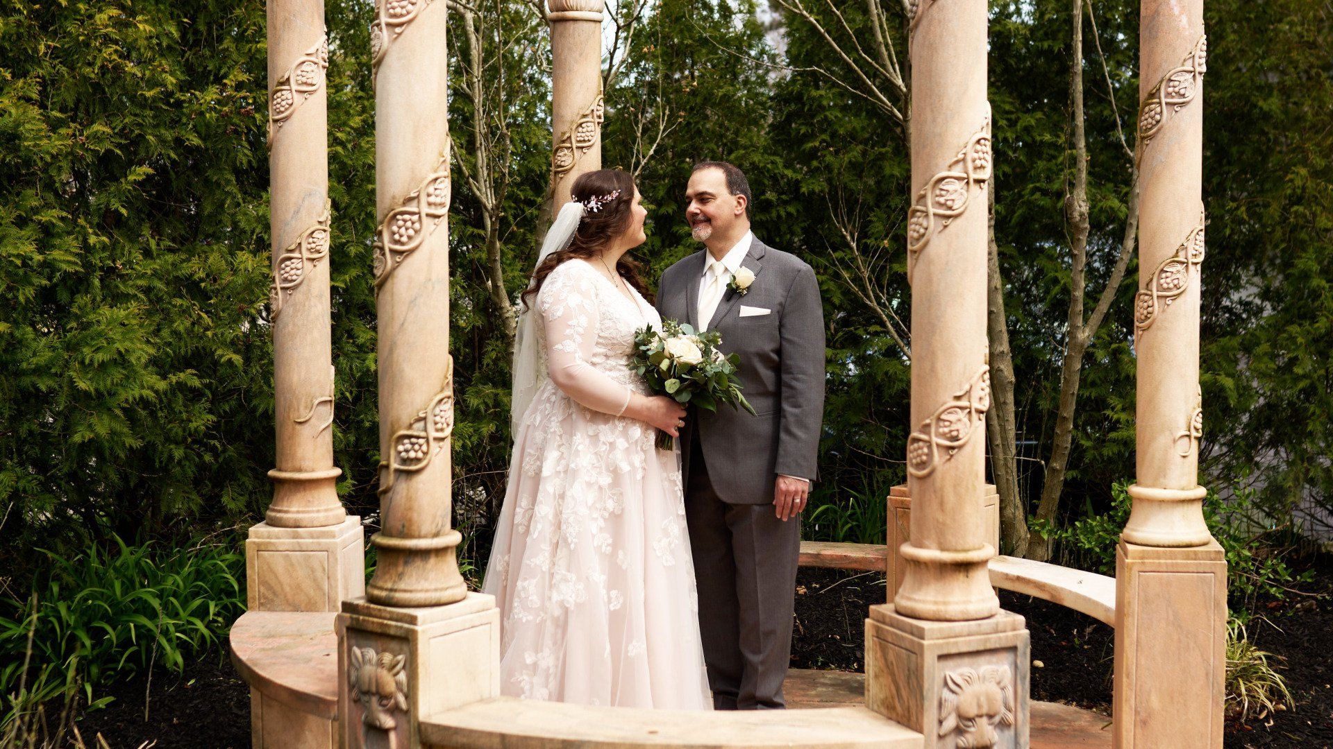A bride and groom are posing for a picture under a gazebo.