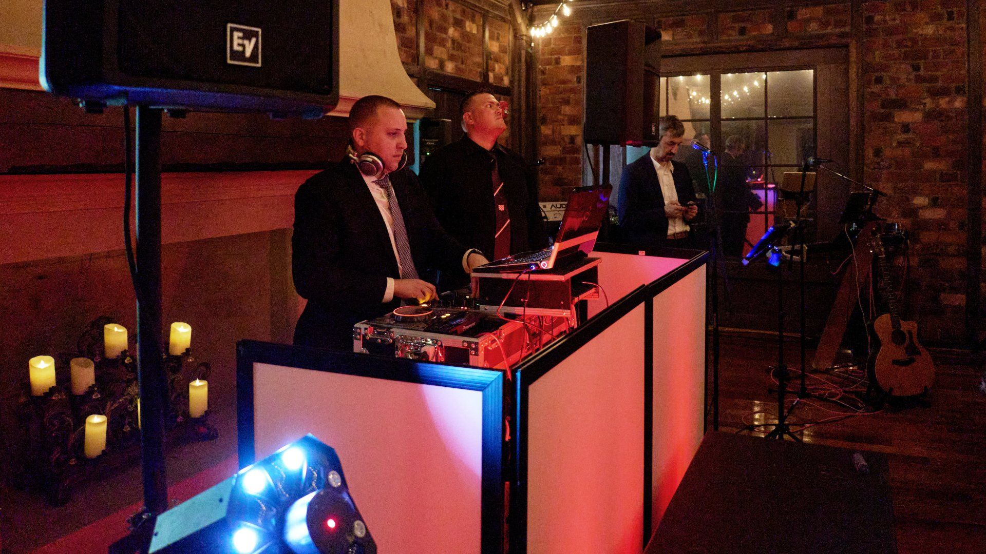 A man in a suit is playing a dj set at a party.