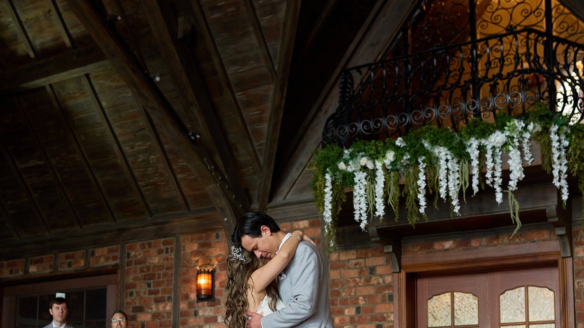 A bride and groom are dancing at their wedding reception in front of a balcony.