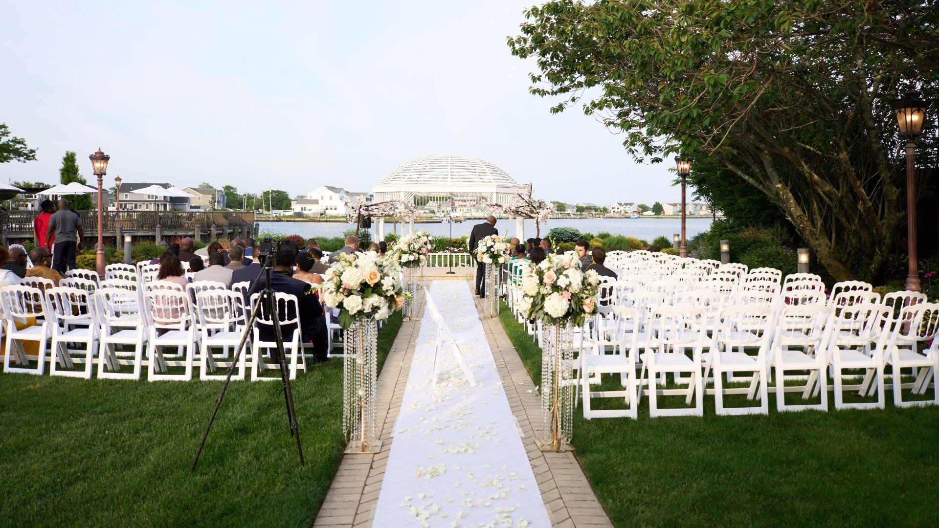 A row of white chairs are lined up for a wedding ceremony