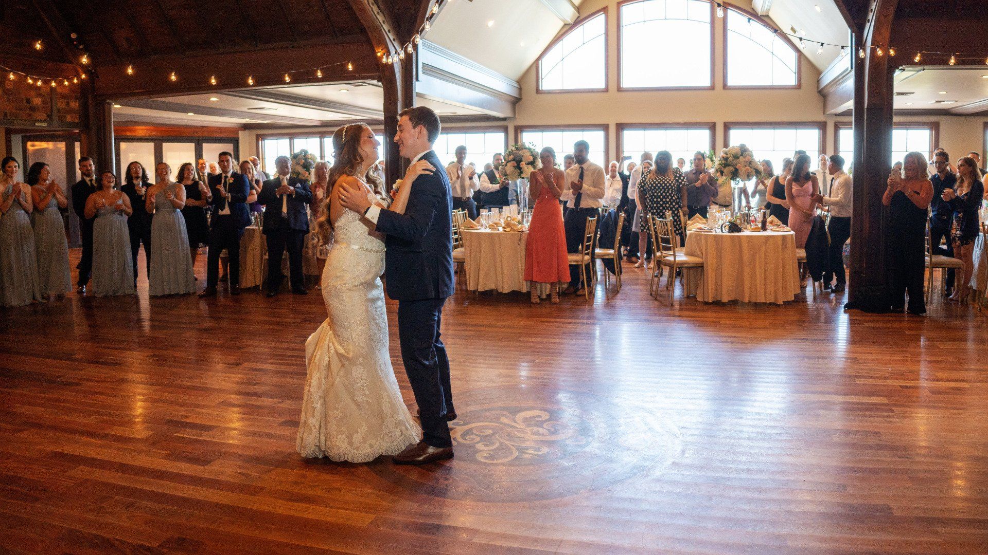 A bride and groom are dancing in a large room at their wedding reception.