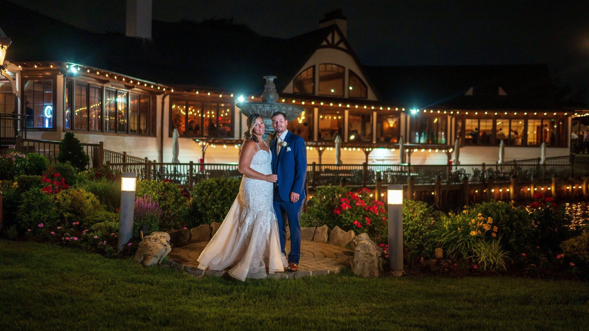 A bride and groom are standing in front of a building at night.