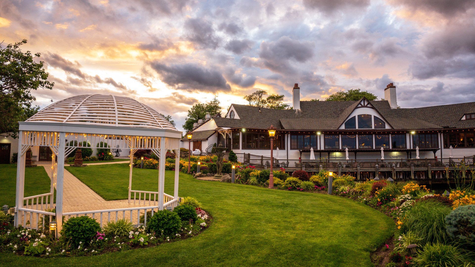 There is a gazebo in the middle of a lush green field in front of a house.