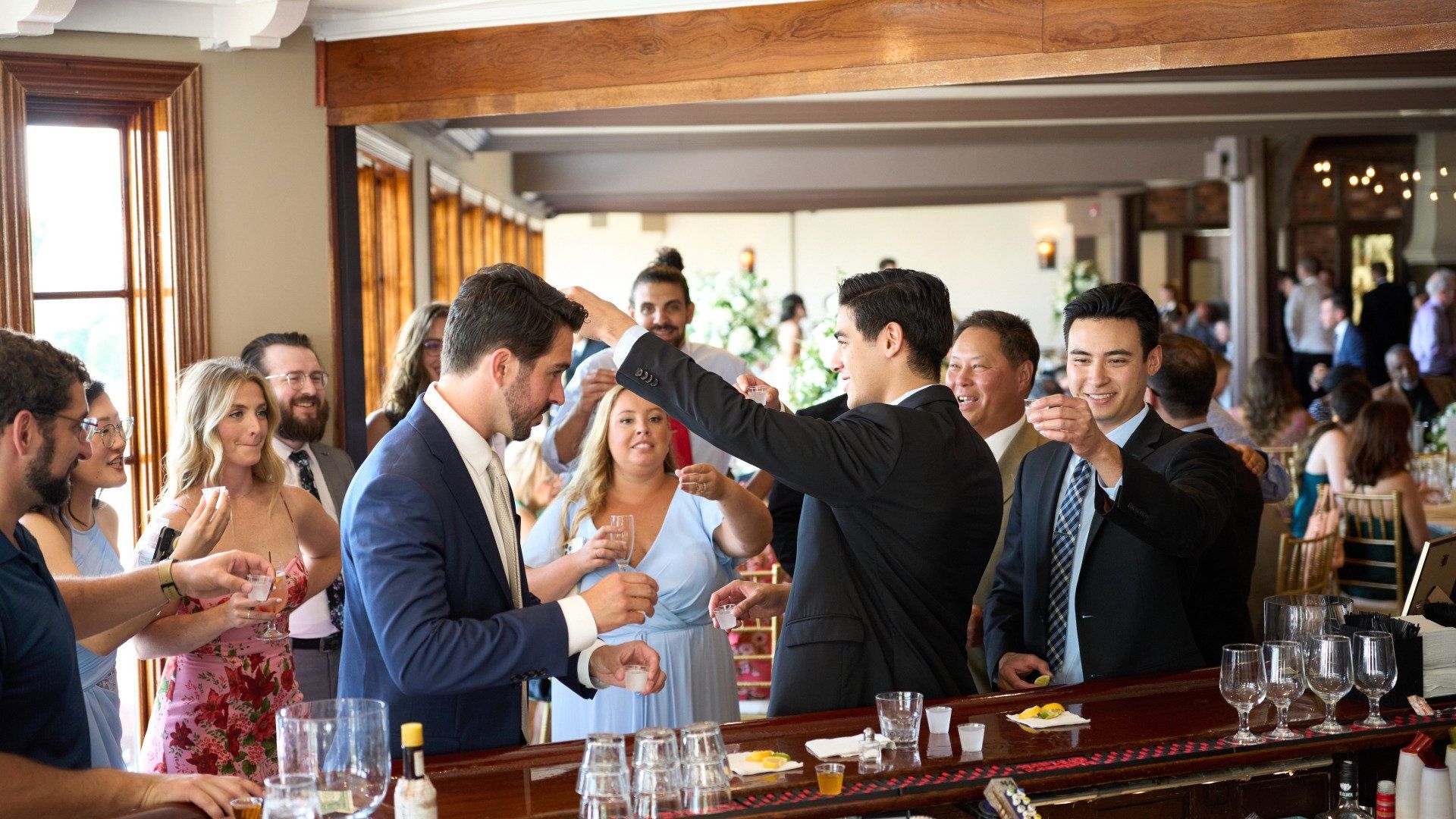 A group of people are standing around a bar.