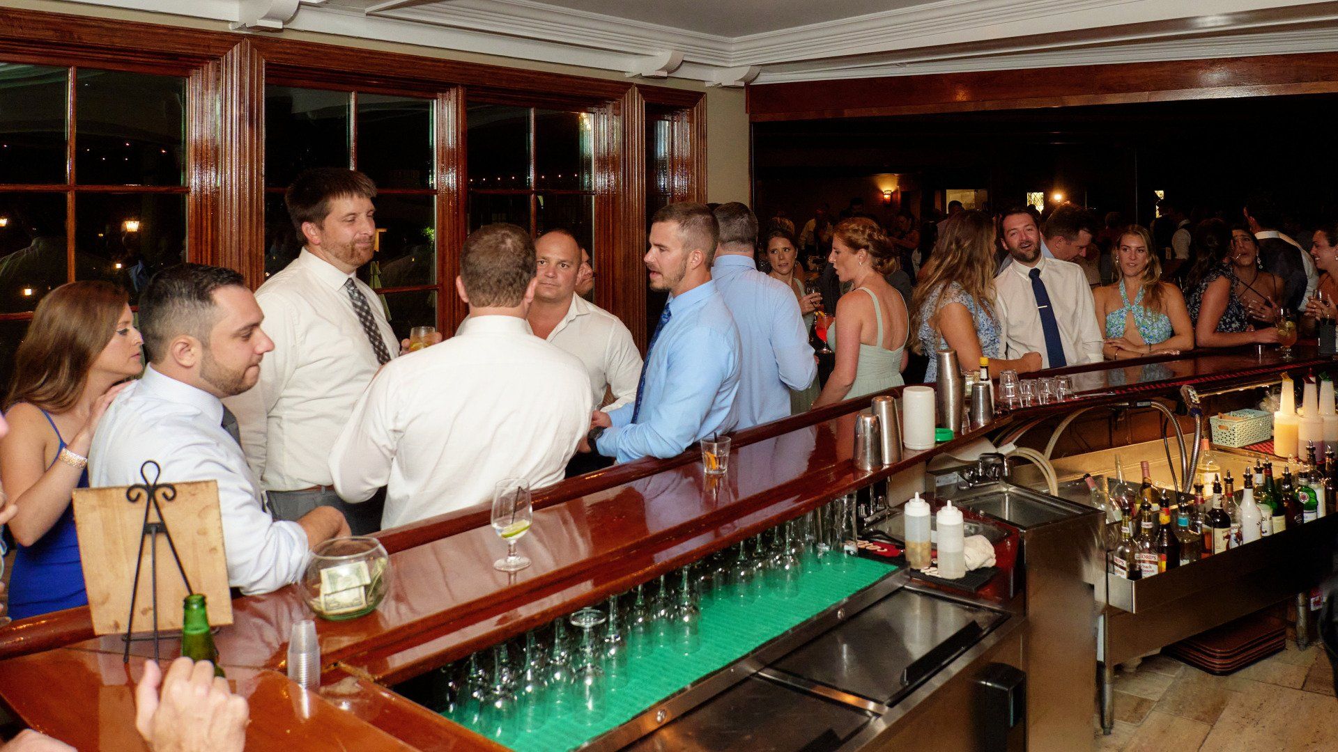 A group of people are sitting at a bar talking to each other.