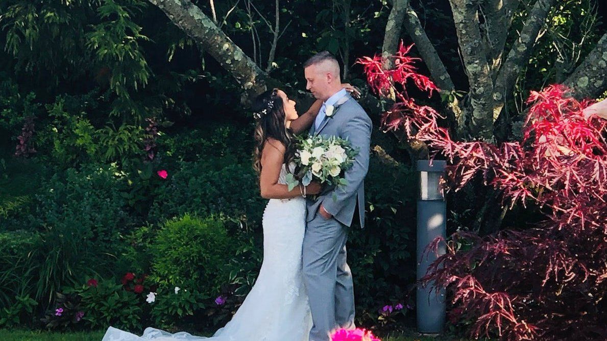 A bride and groom are kissing in front of a tree.