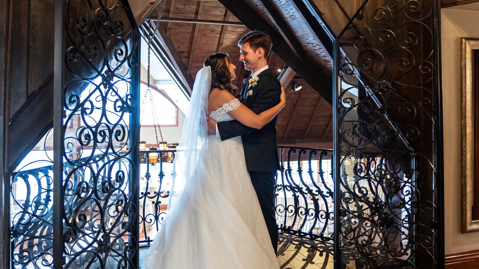 A bride and groom are standing next to each other on a balcony.