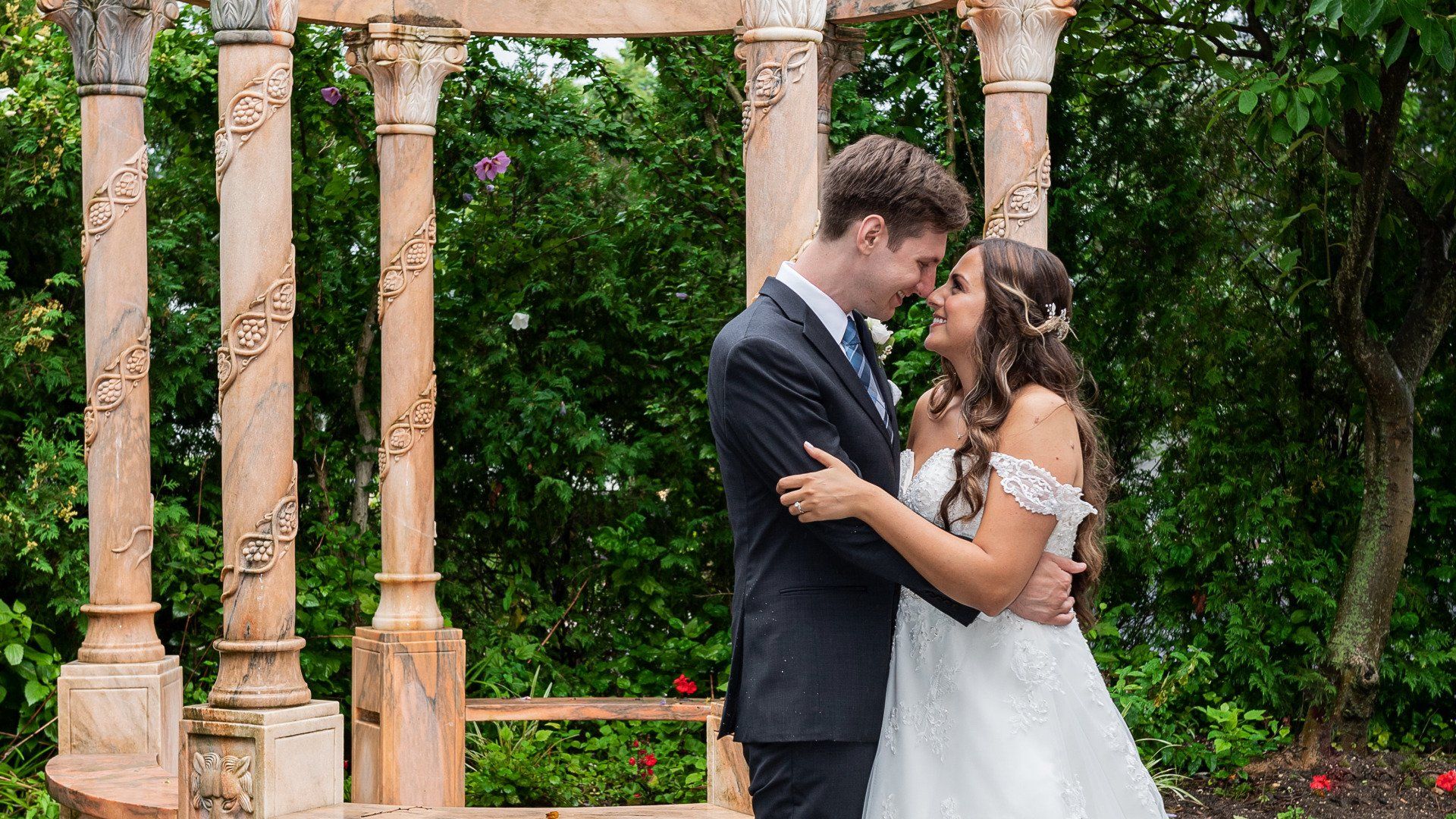 A bride and groom are posing for a picture in front of a gazebo.