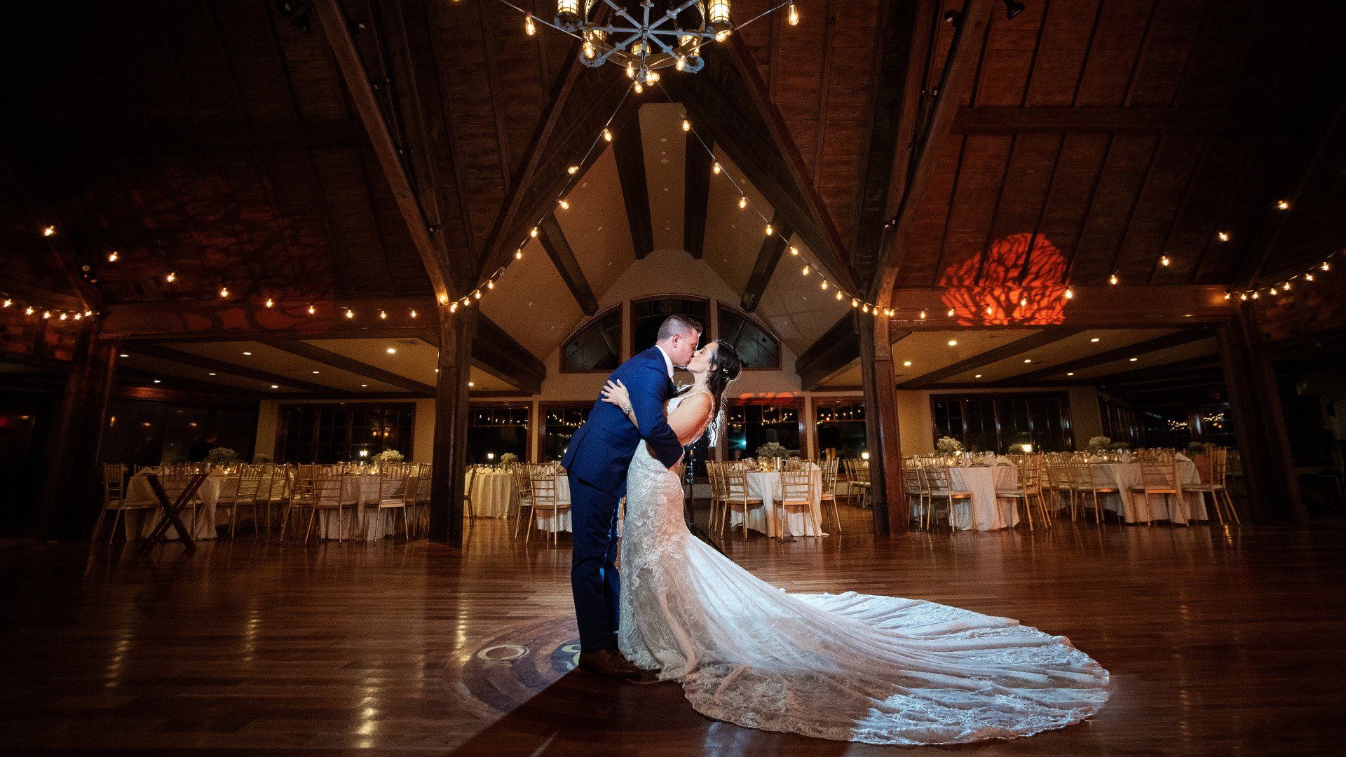 A bride and groom are kissing on the dance floor at their wedding reception.