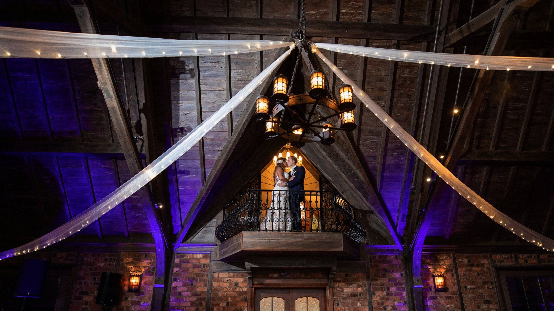 A bride and groom are standing on a balcony at their wedding reception.