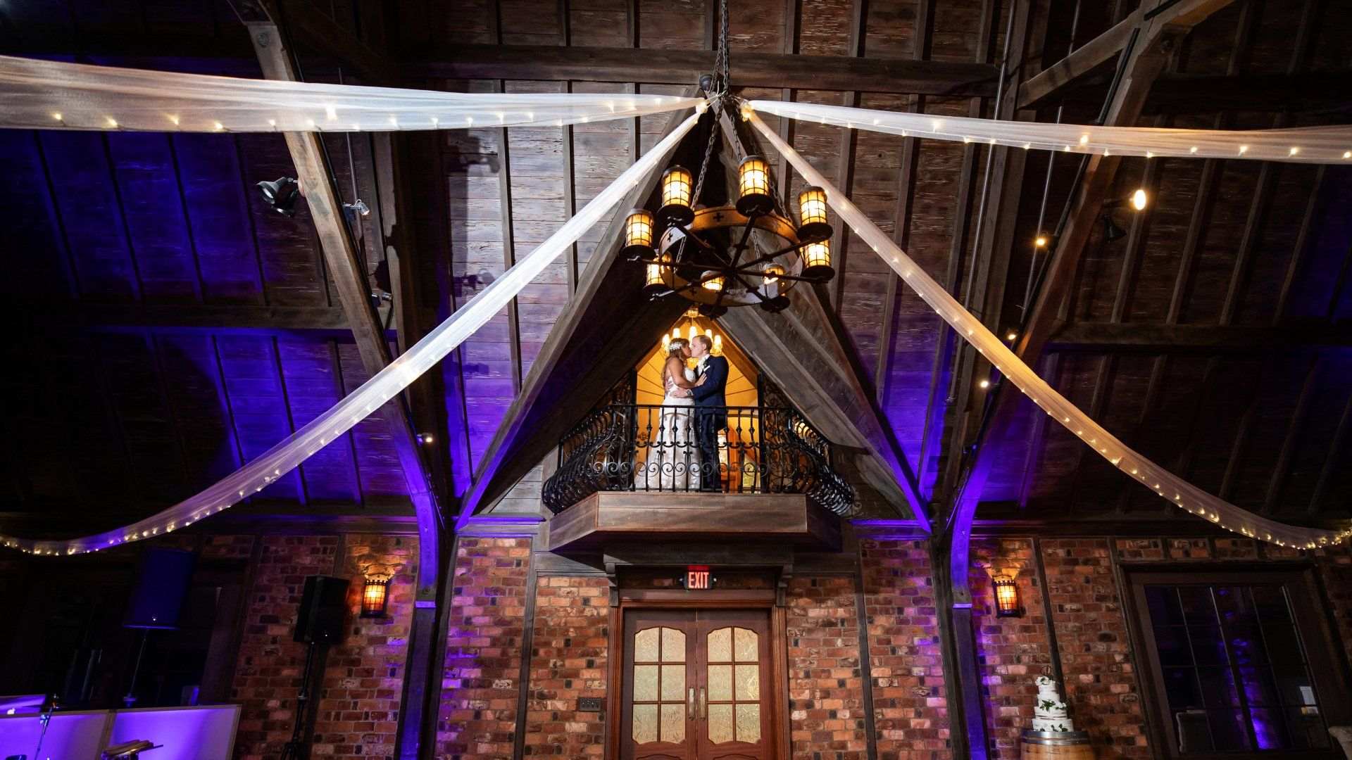 A bride and groom are standing on a balcony at their wedding reception.