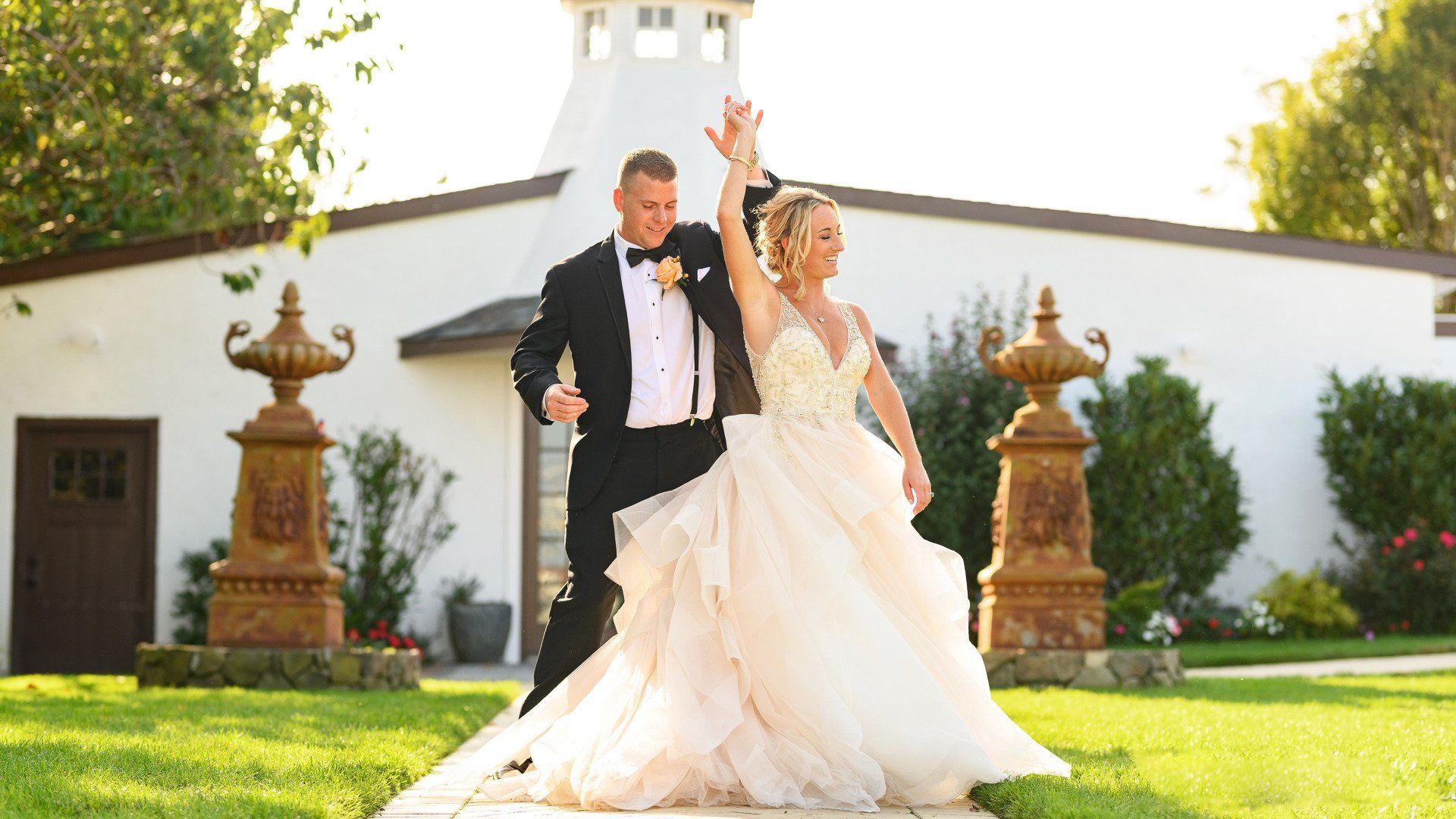 A bride and groom are posing for a picture in front of a white building.