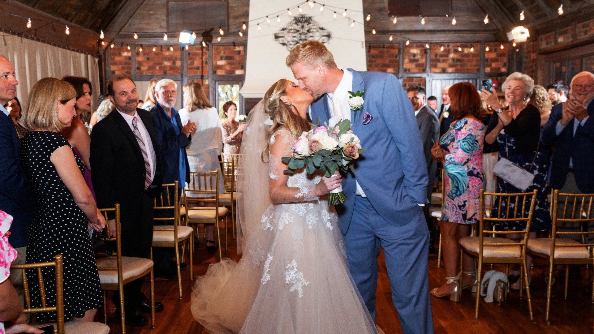 A bride and groom kissing at the end of their wedding ceremony.