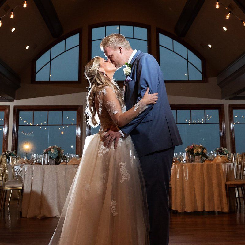 A bride and groom kissing in front of a large window