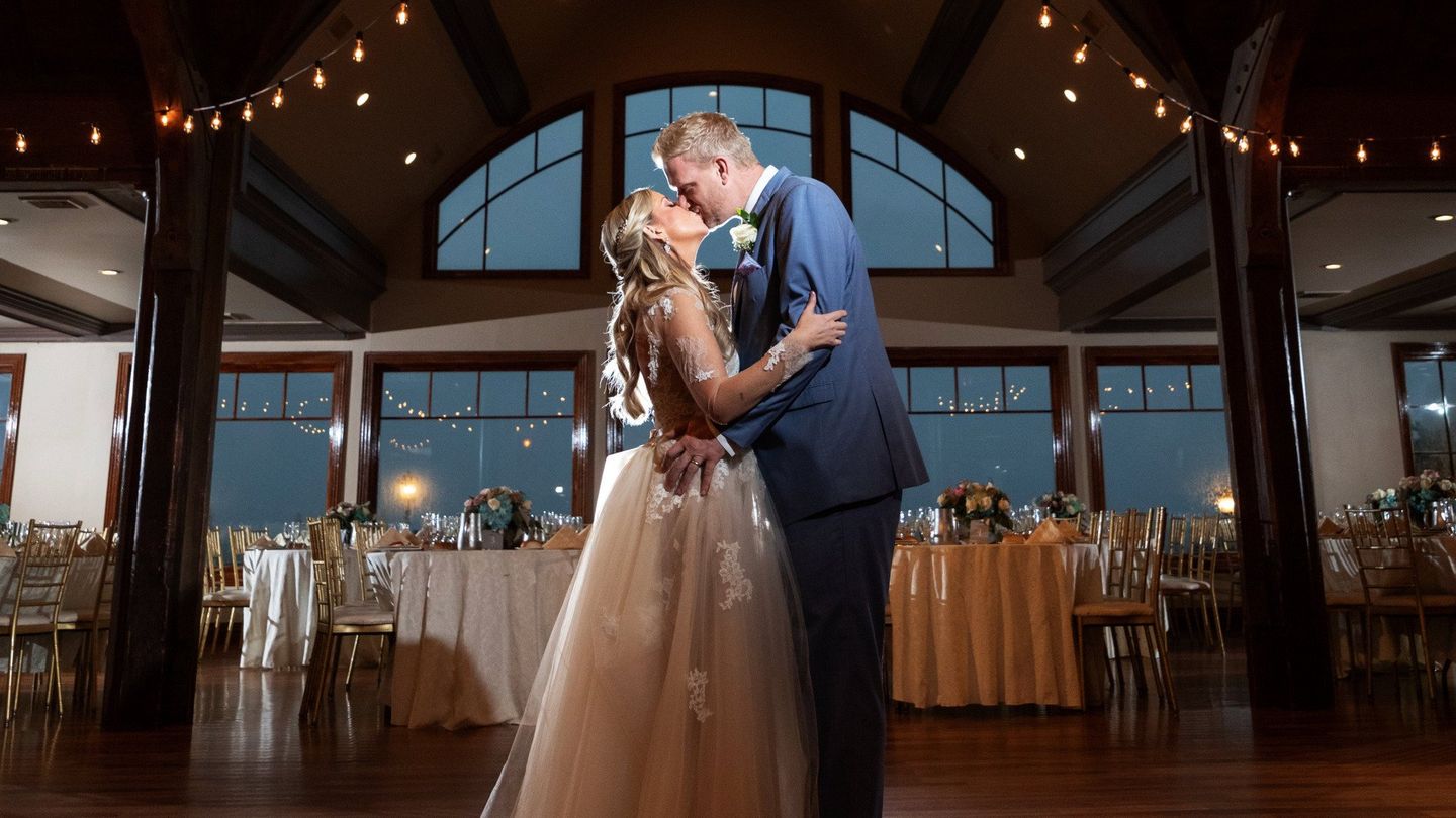a bride and groom are kissing in a large room at their wedding reception .