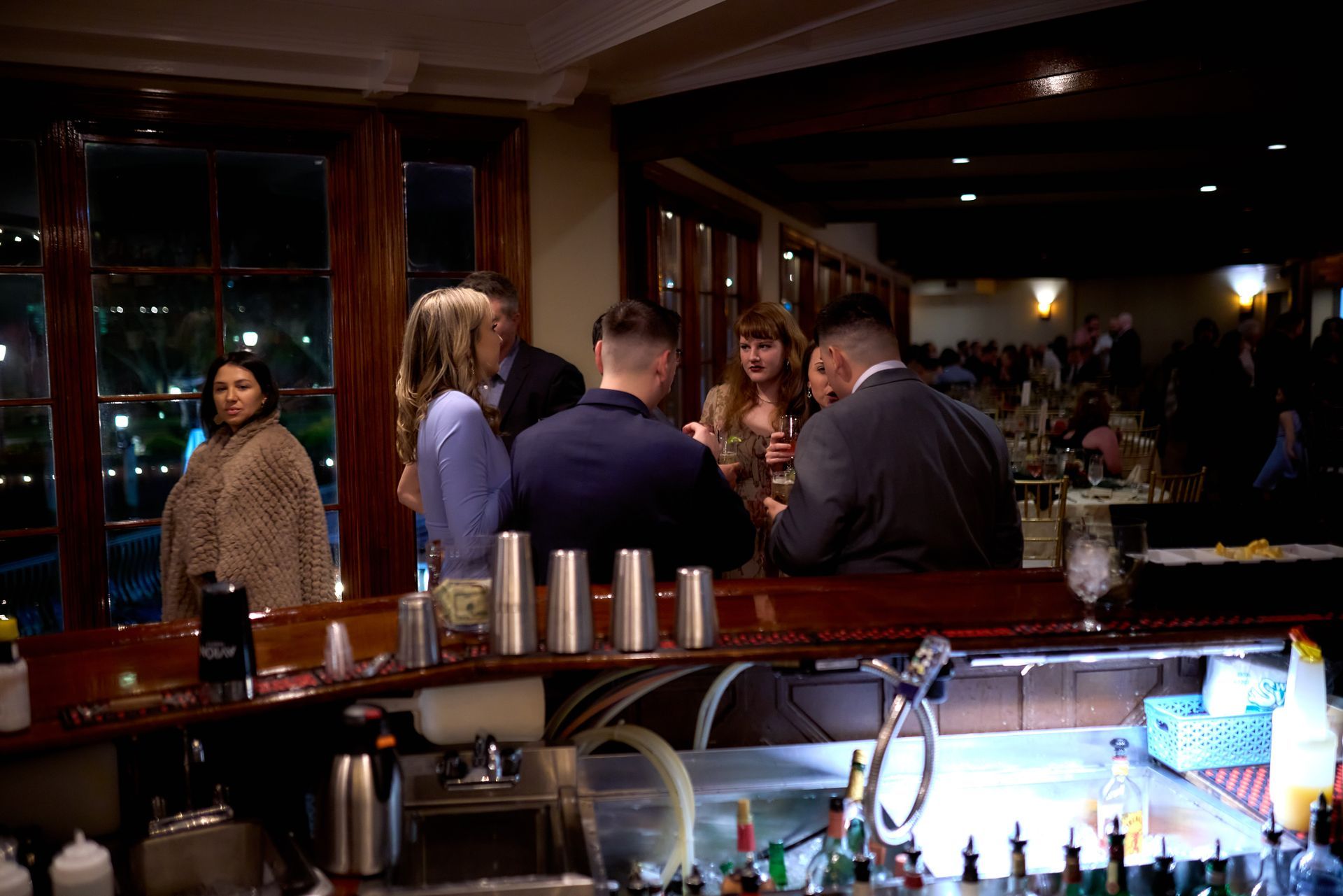 A group of people are standing around a bar in a restaurant.