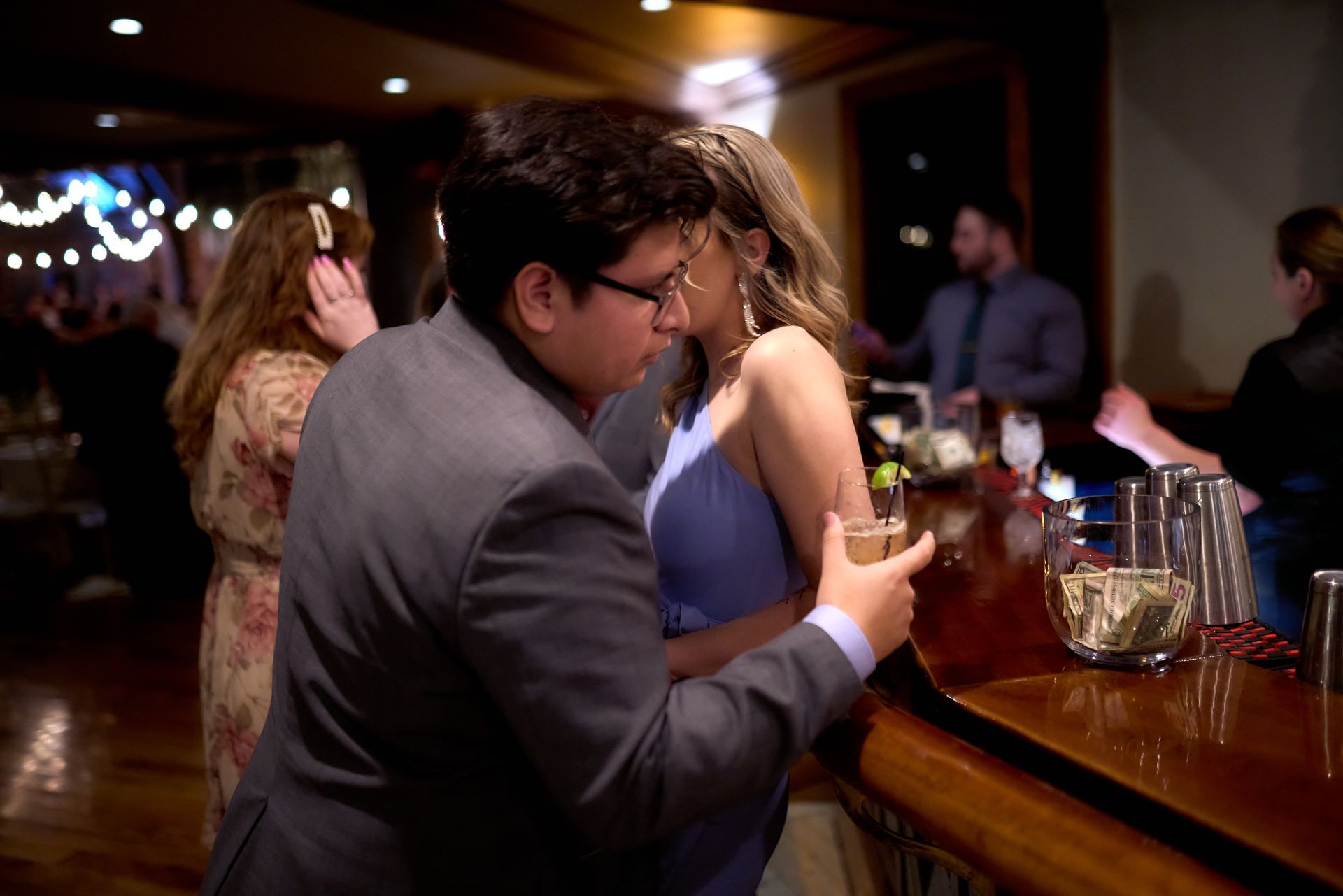 A man in a suit is touching a woman 's arm at a bar.