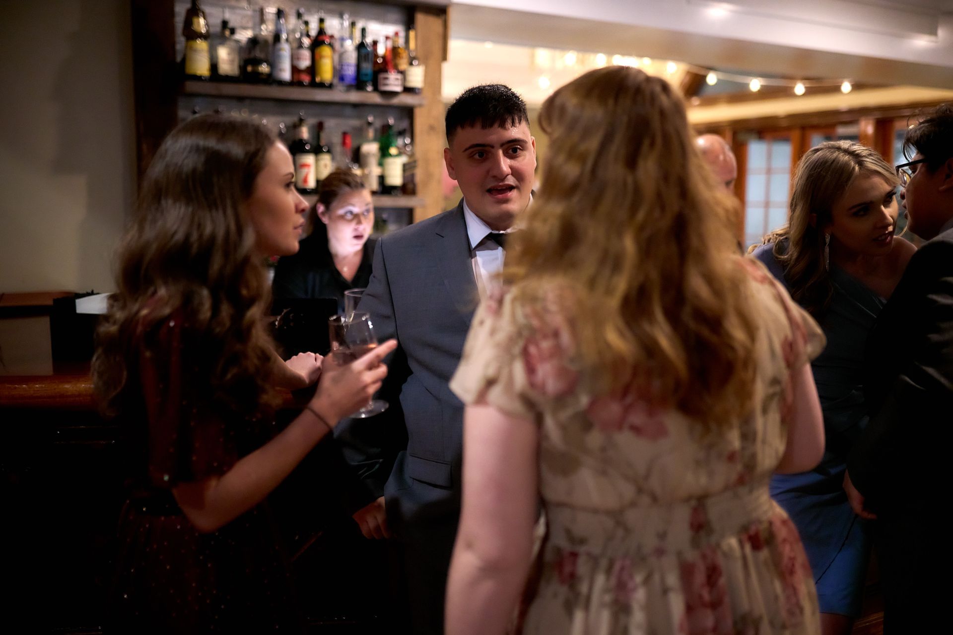 A group of people are standing in a room talking to each other.