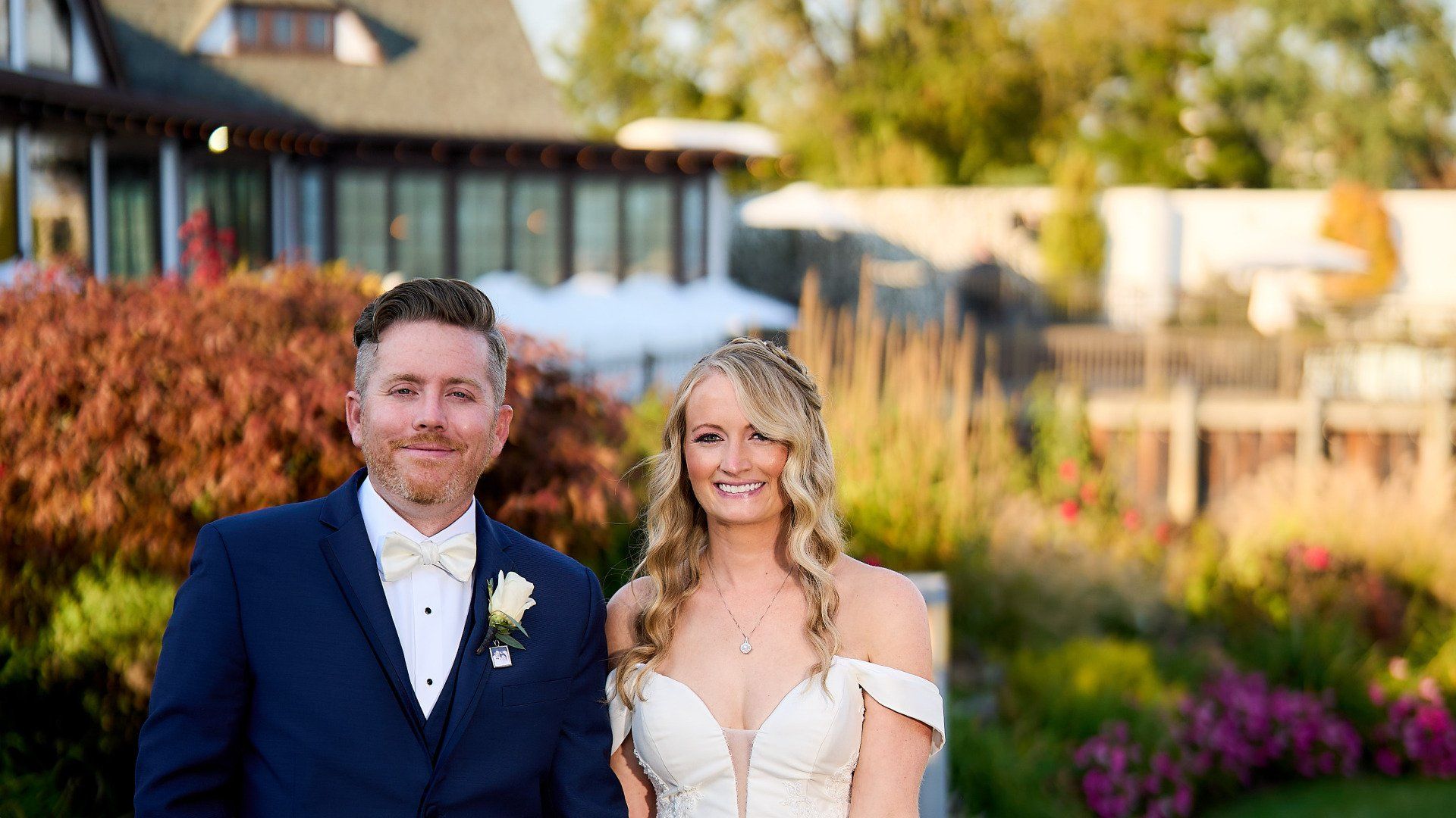 A bride and groom are posing for a picture in front of a house.