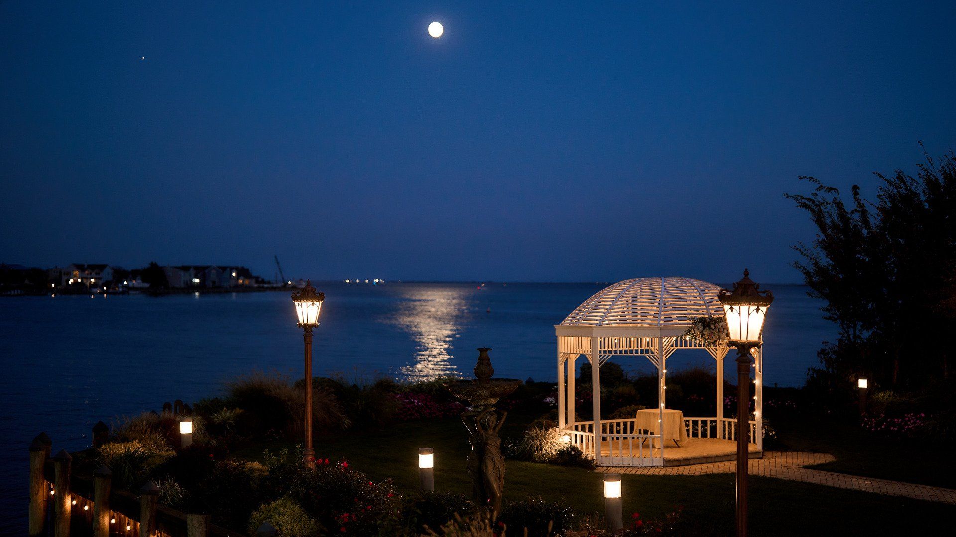 A gazebo overlooking a body of water at night