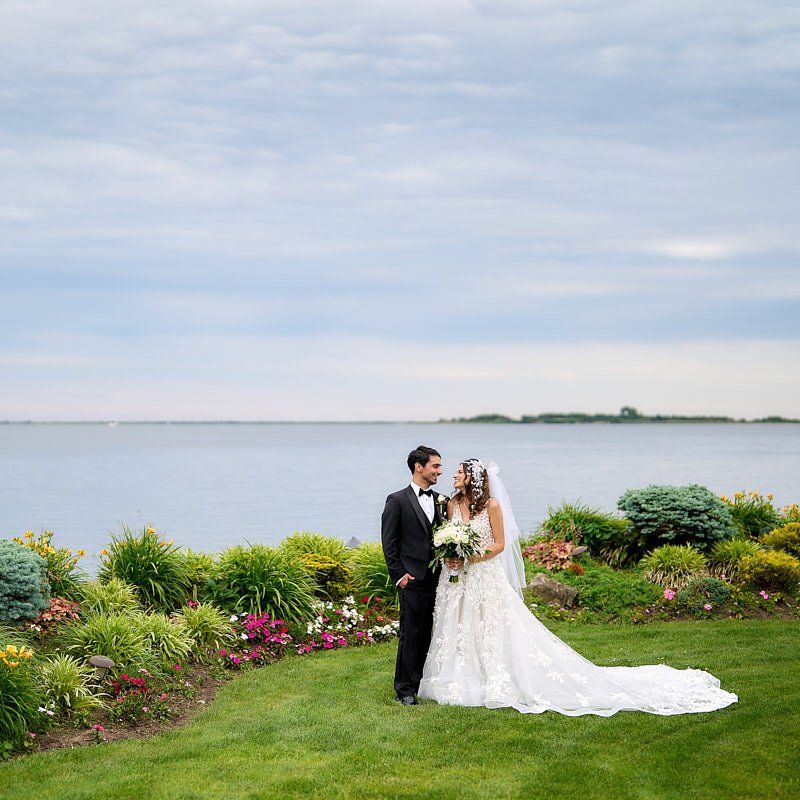 A bride and groom are posing for a picture in front of a body of water.