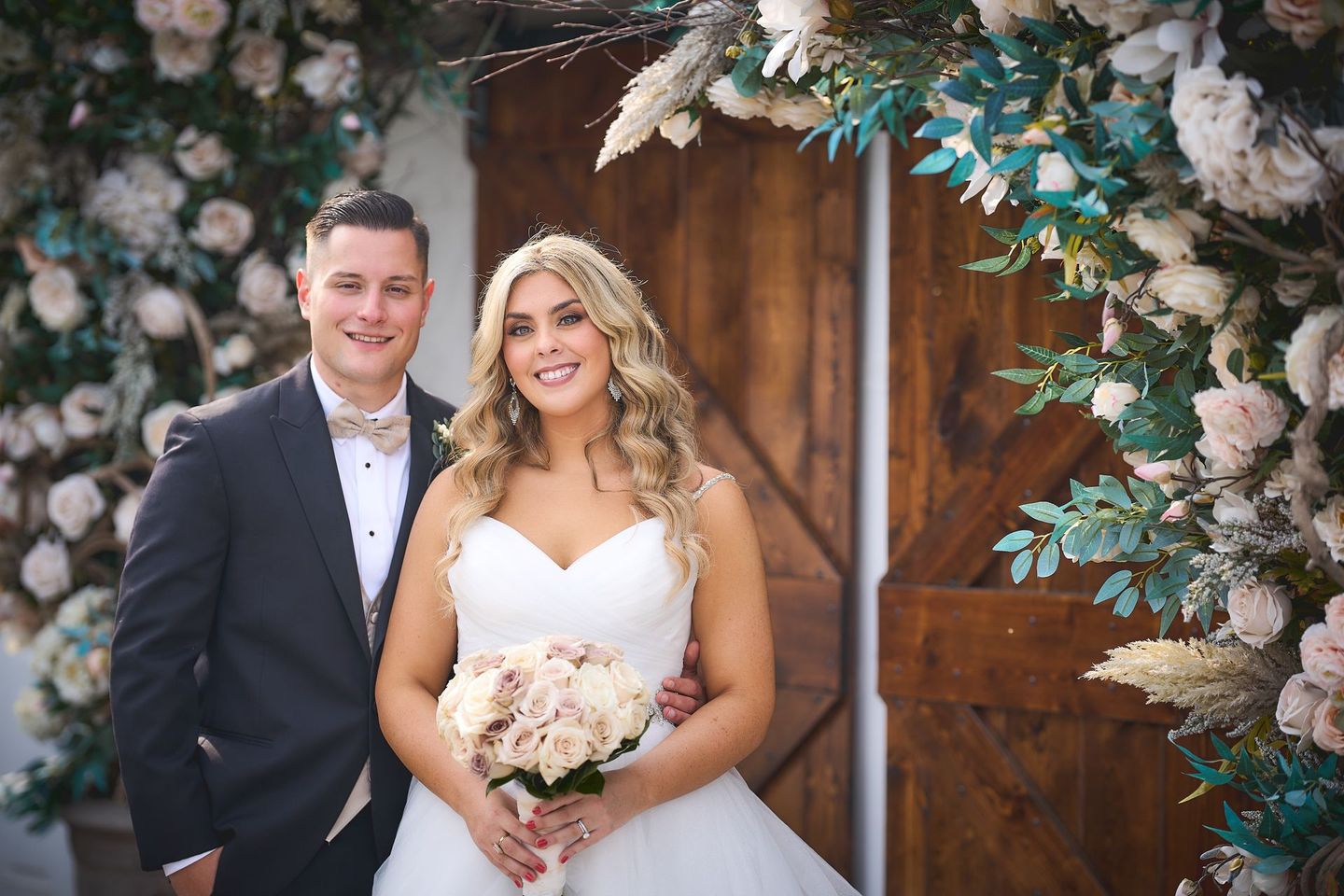 a bride and groom are posing for a picture in front of a wooden door .