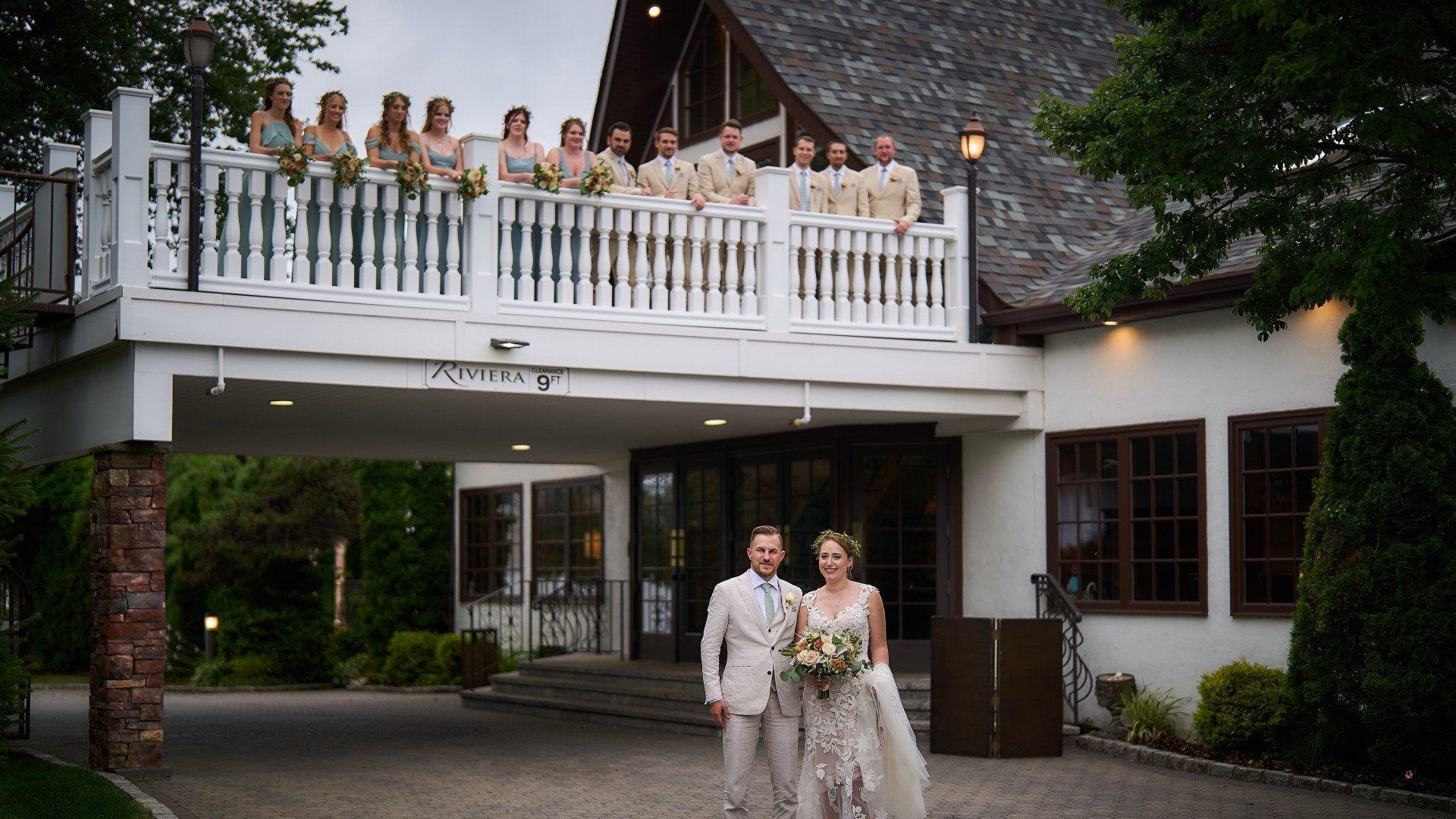 A bride and groom are standing in front of a building with their wedding party.