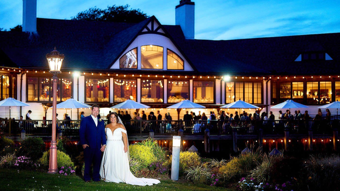 A bride and groom pose for a picture in front of a large building