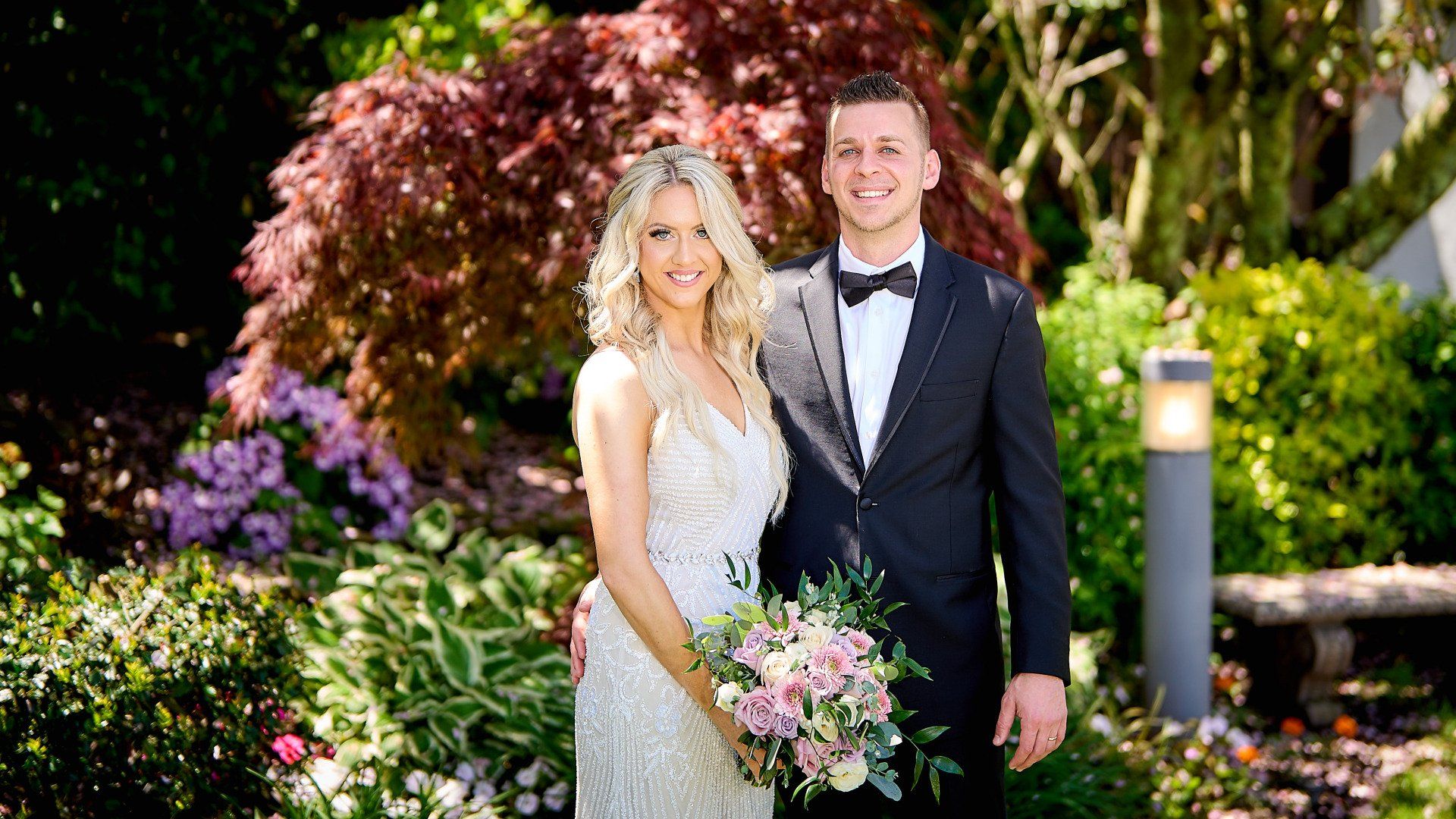 A bride and groom are posing for a picture in a garden.